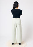 Person wearing a black top and pale green pants on a white background