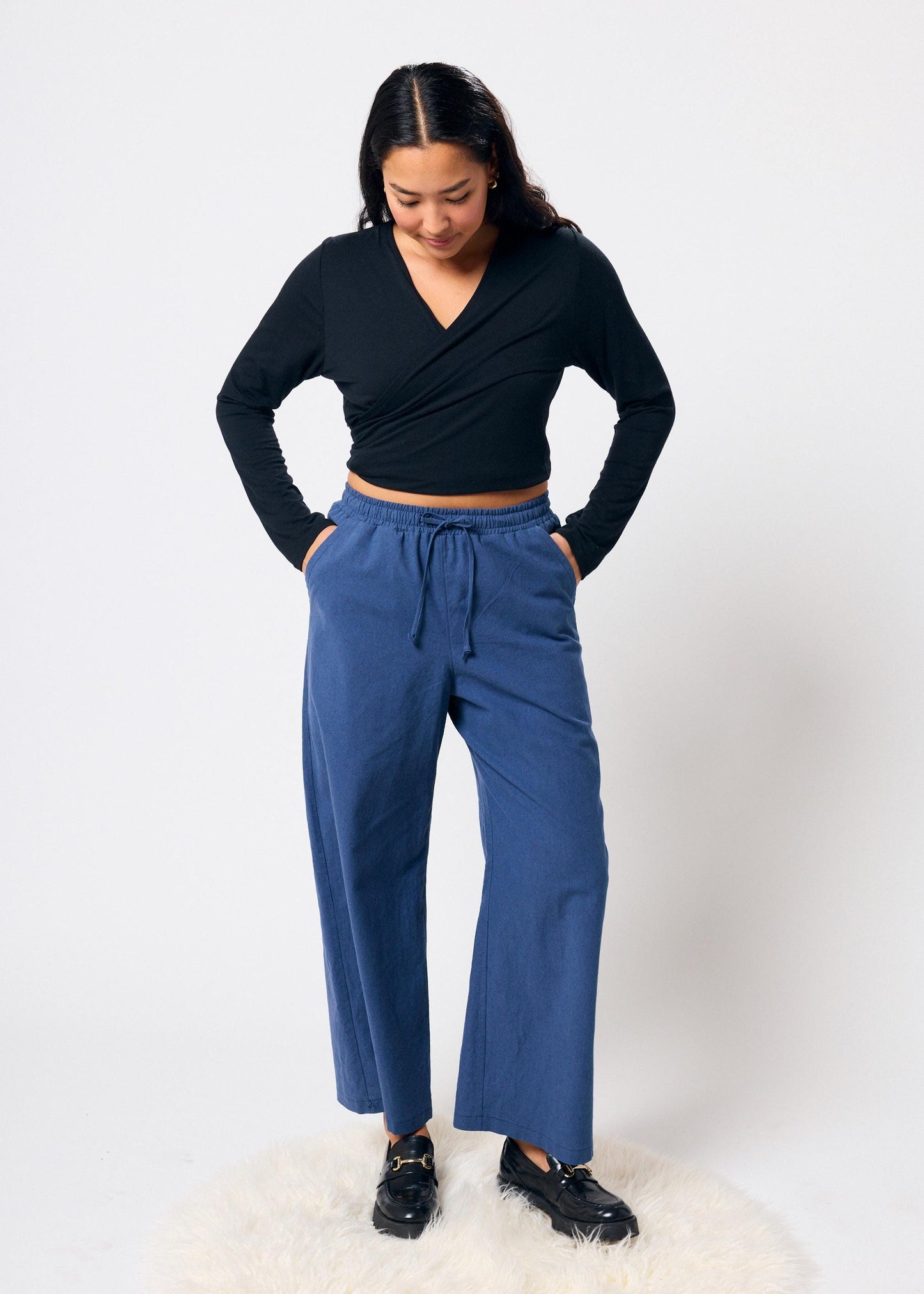 Woman wearing a black top and blue pants on a white background