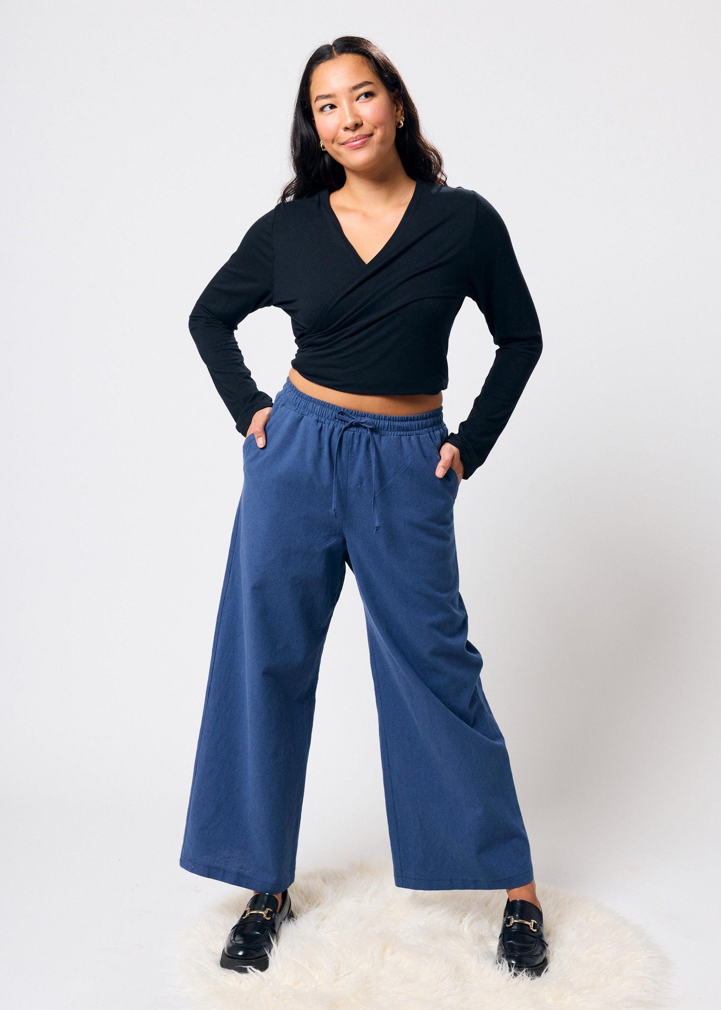 Woman wearing a black top and blue pants on a white background