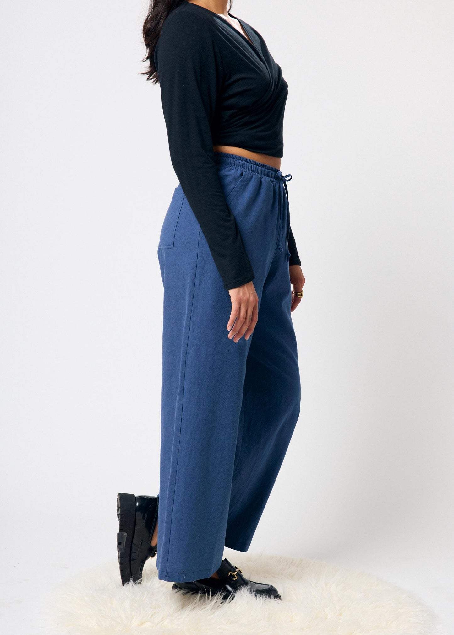 Person wearing a black long-sleeve top and blue pants on a white background