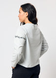 Woman wears cropped pale blue long sleeve t-shirt with black embroidered barbed wire design on left arm
