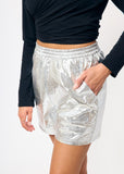 Person wearing silver metallic shorts with a plain background