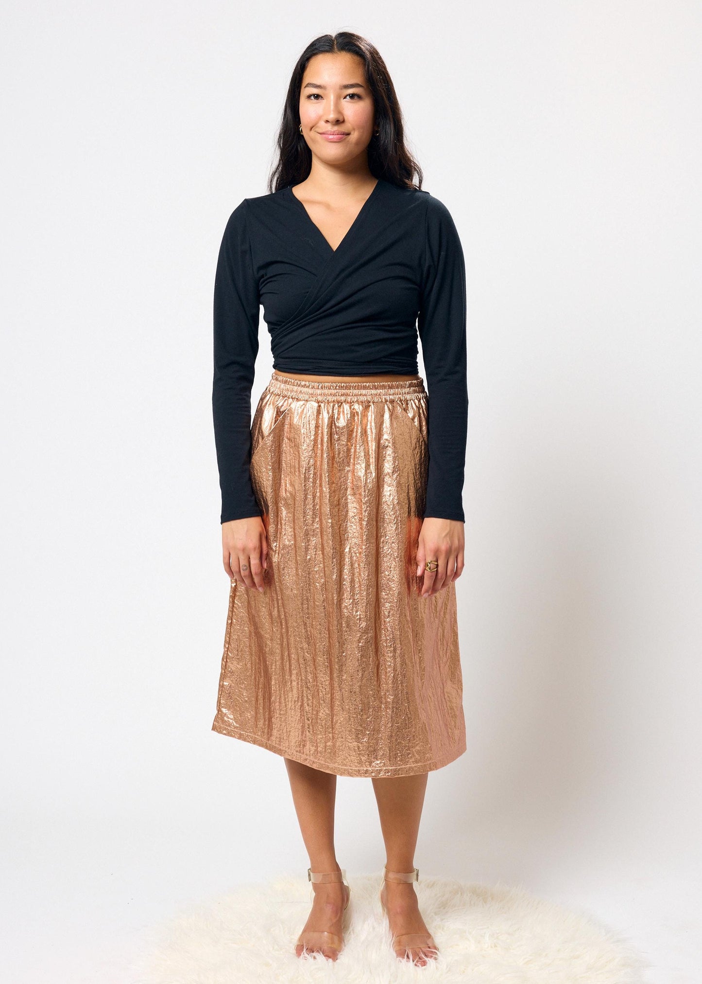 Woman wearing a black top and bronze skirt on a white background