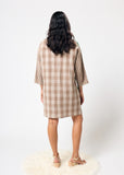 Woman wearing a plaid dress standing on a white background