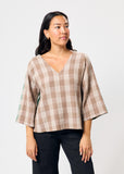 Woman wearing a plaid top with a plain background