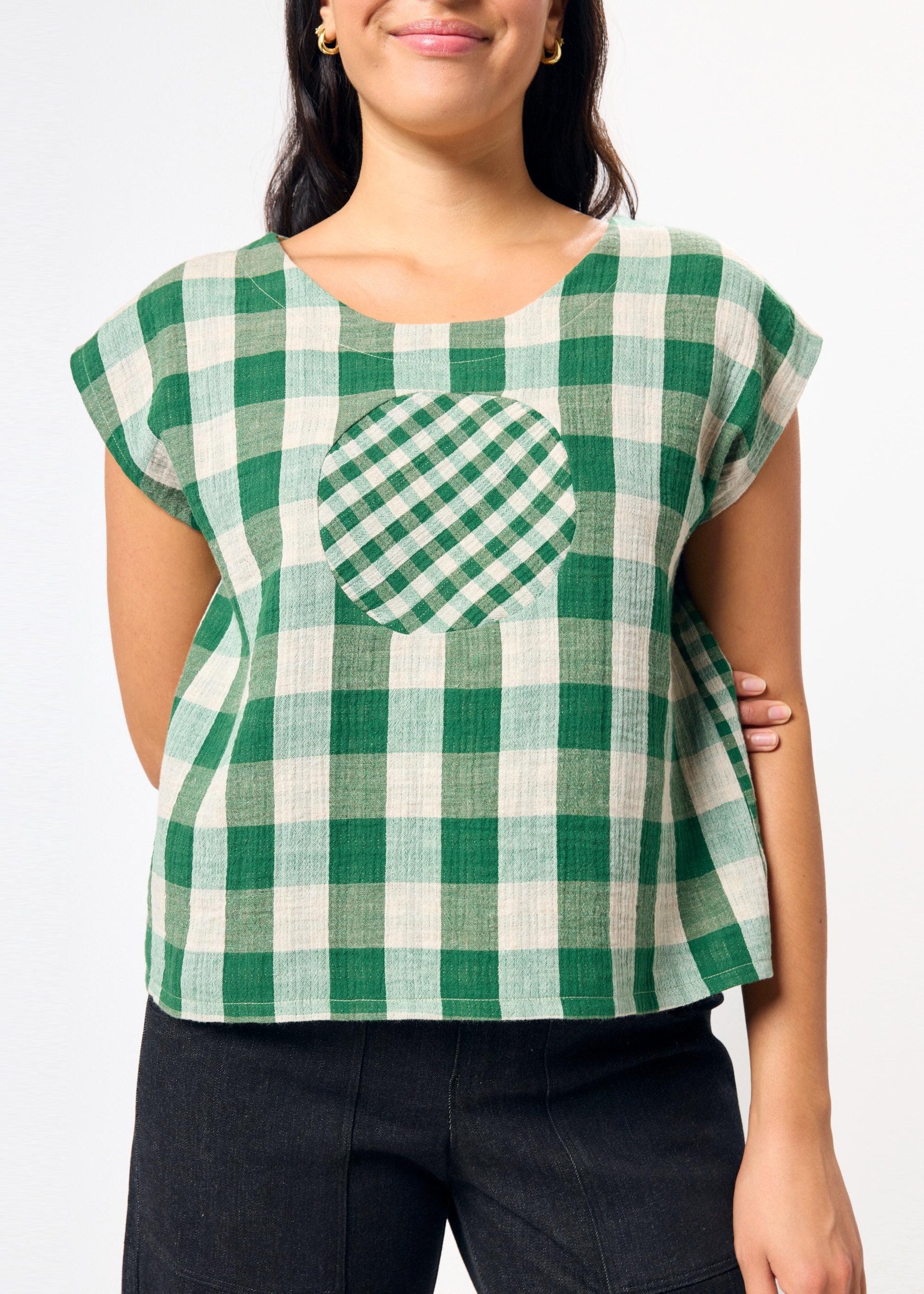 Green and white checkered top with a circle design on the chest on a plain background