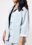 Light blue denim jacket with button details on a plain background