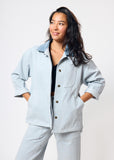 Woman wearing a light blue jacket and pants on a white background