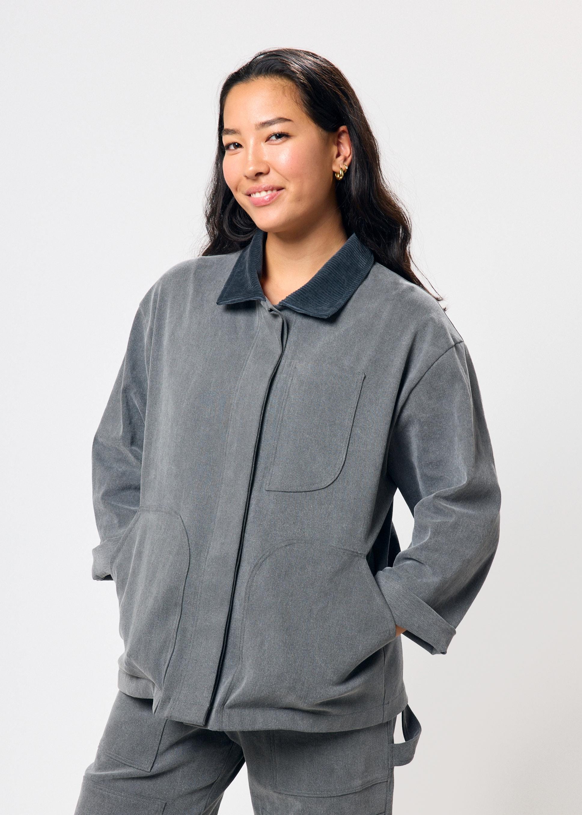 Woman wearing a gray outfit with a dark collar against a white background