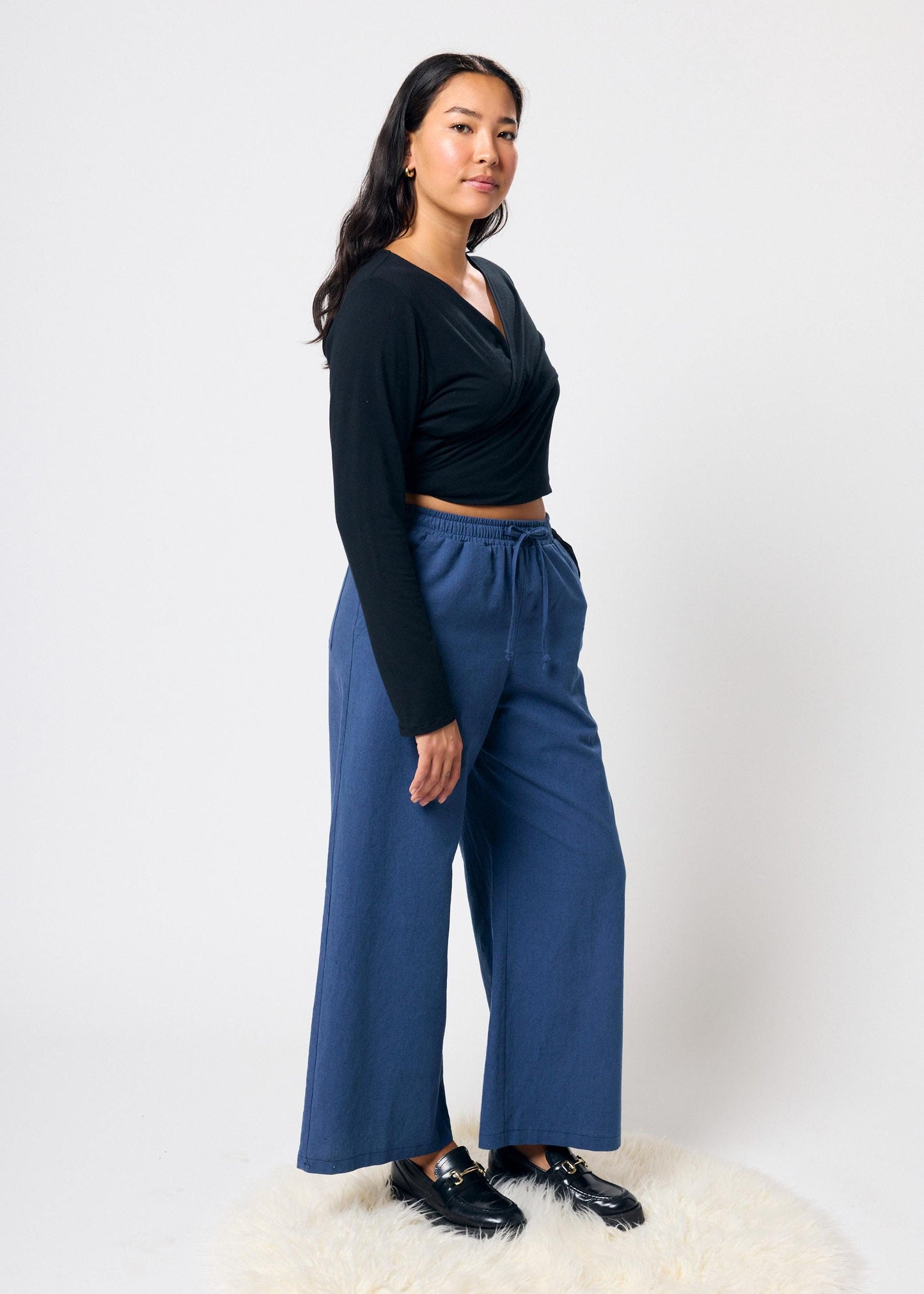 Woman wearing a black top and blue pants on a white background