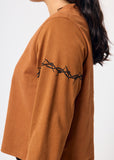 Brown shirt with barbed wire design on sleeve against a white background