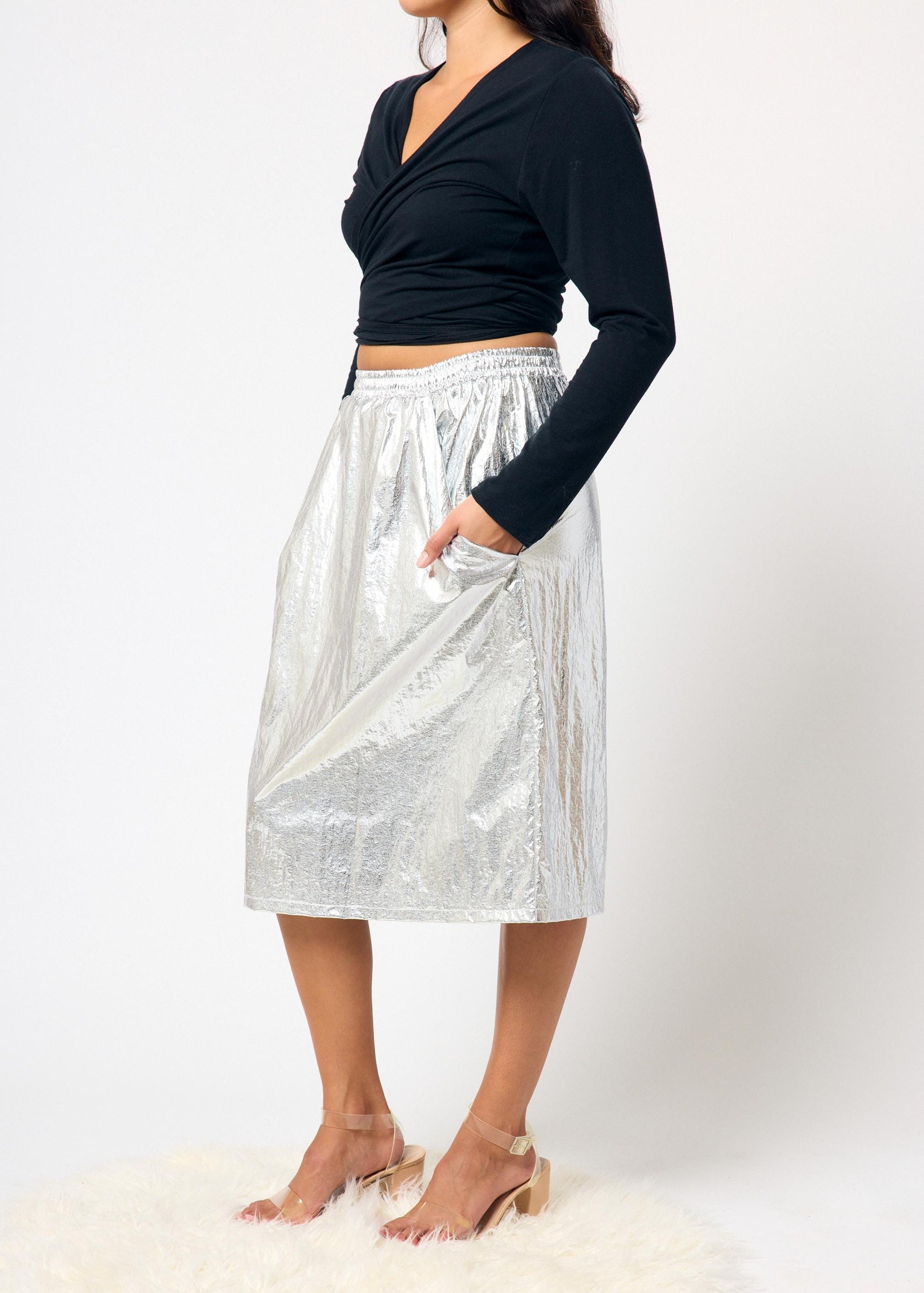 Person wearing a black top and silver skirt on a white background