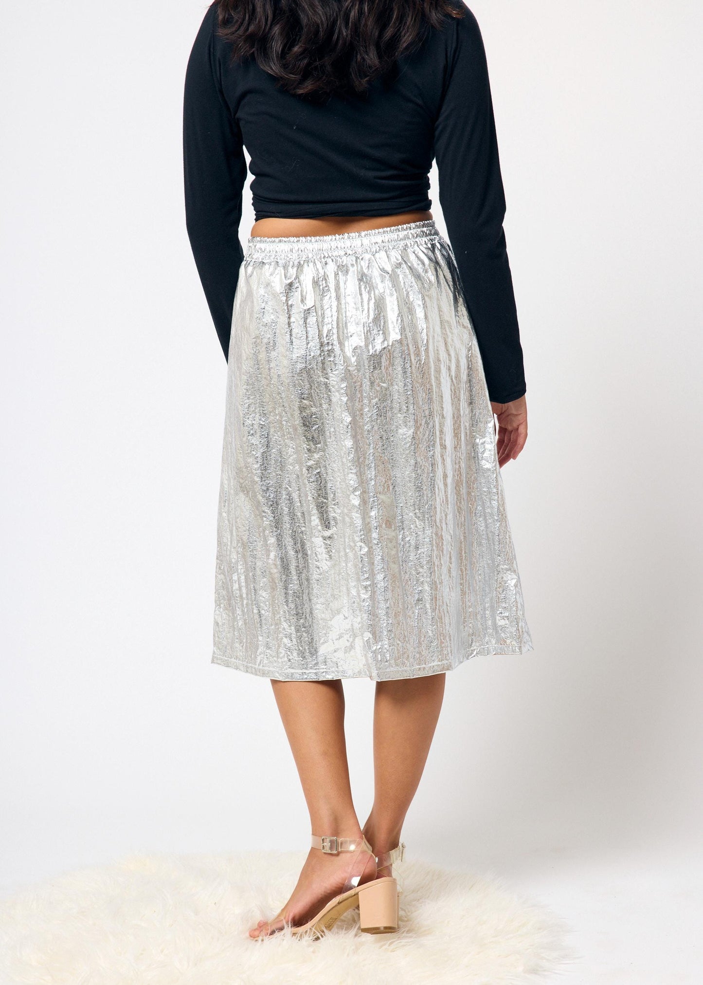 Person wearing a silver skirt and black top on a white background