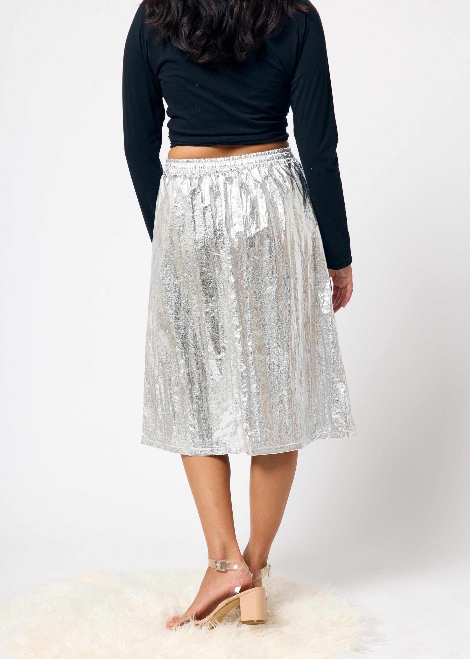 Person wearing a silver skirt and black top on a white background