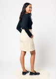 Woman wearing a black top and beige denim skirt on a white background