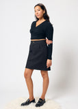 Woman wearing a black top and black denim skirt on a white background