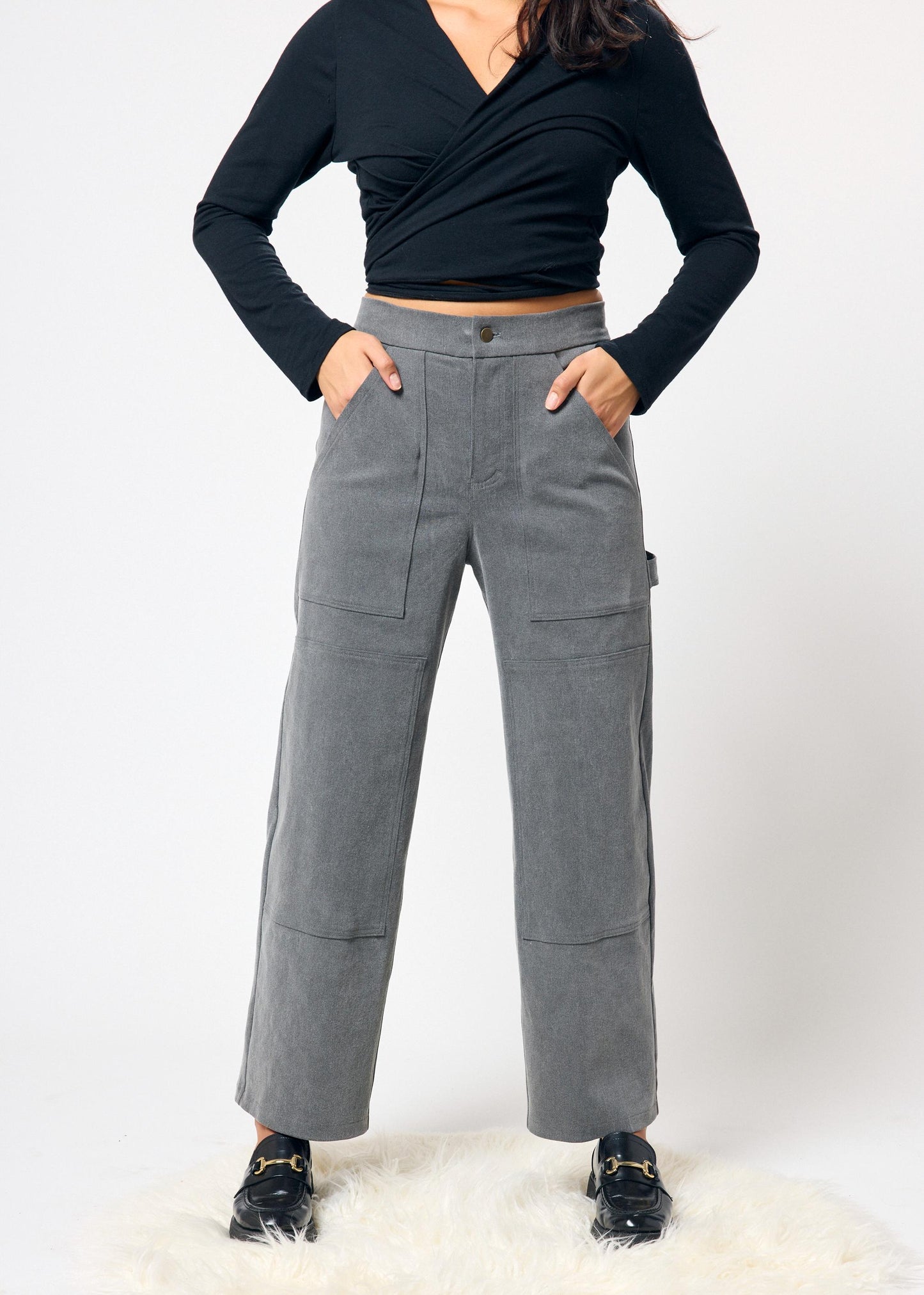 Person wearing gray pants and a black top on a white background