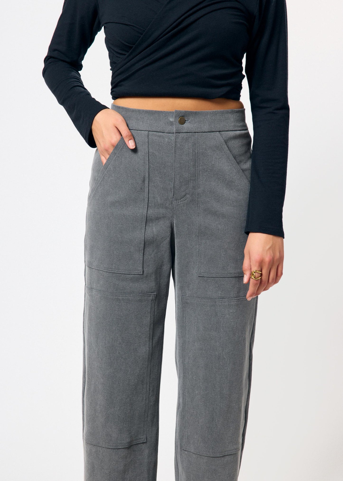 Person wearing gray pants and a black top on a white background