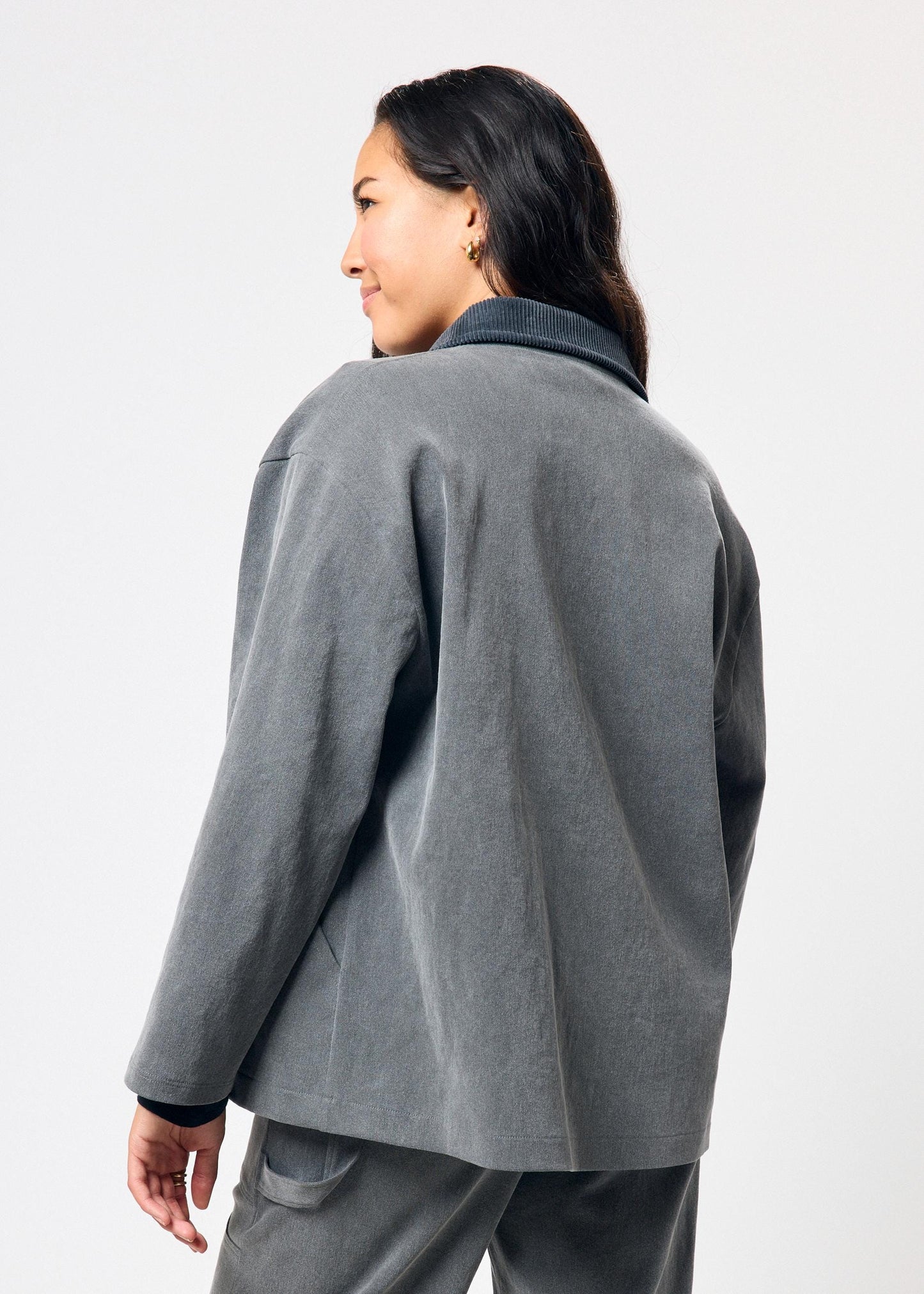 Person wearing a gray jacket and pants on a white background