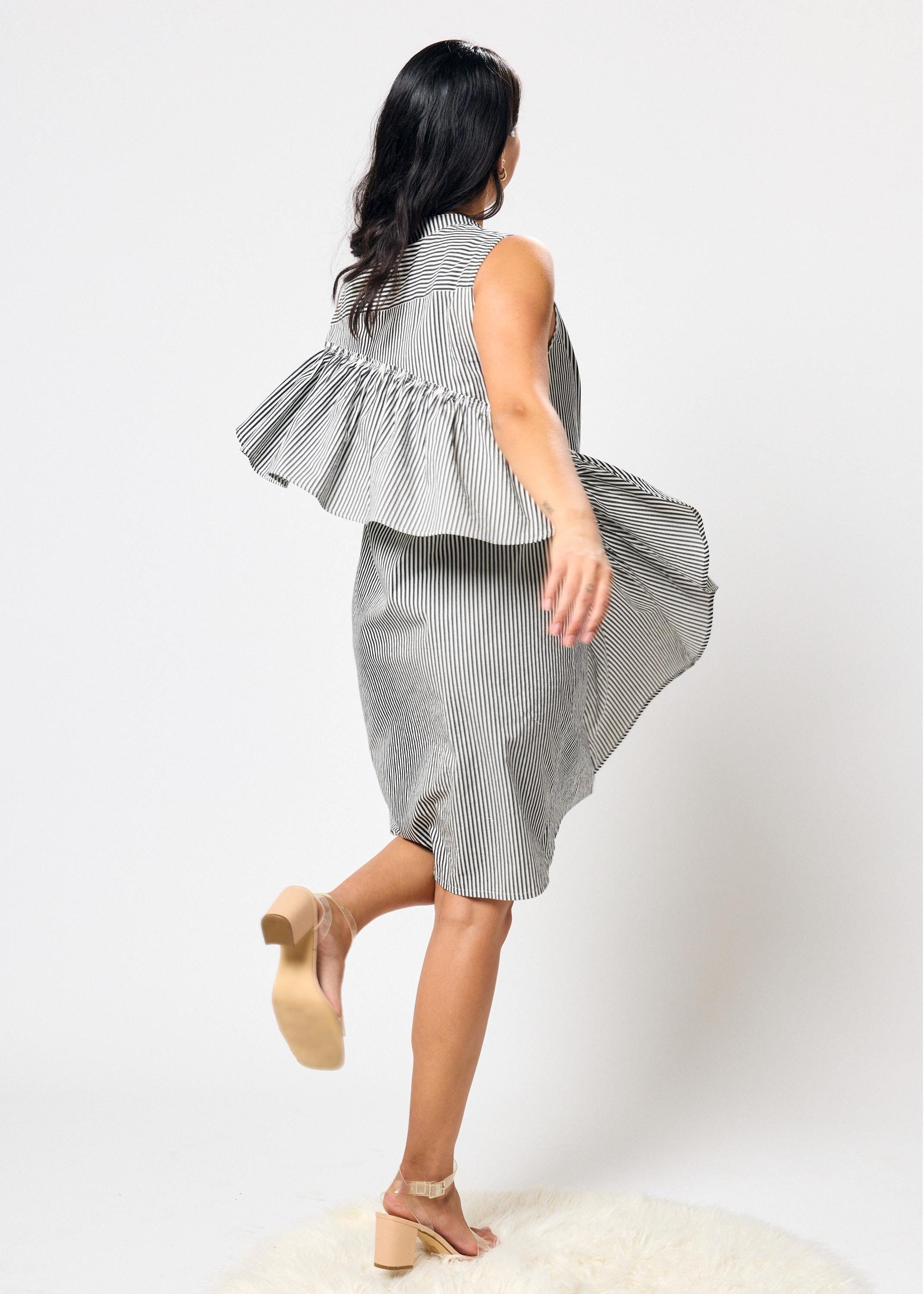 Woman wearing a black and white striped dress with ruffles on a white background