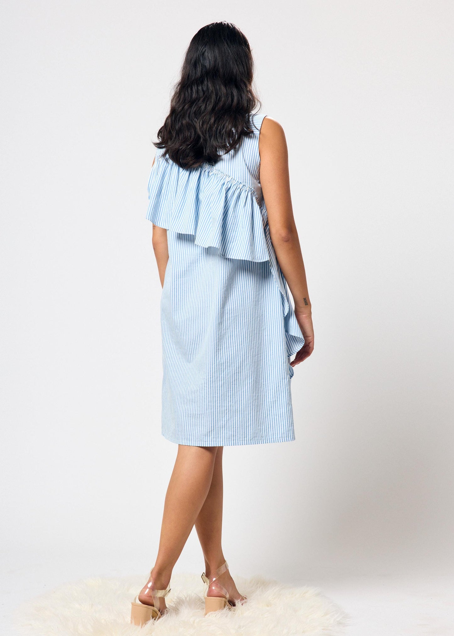 Woman wearing a blue and white striped dress with ruffles on a white background