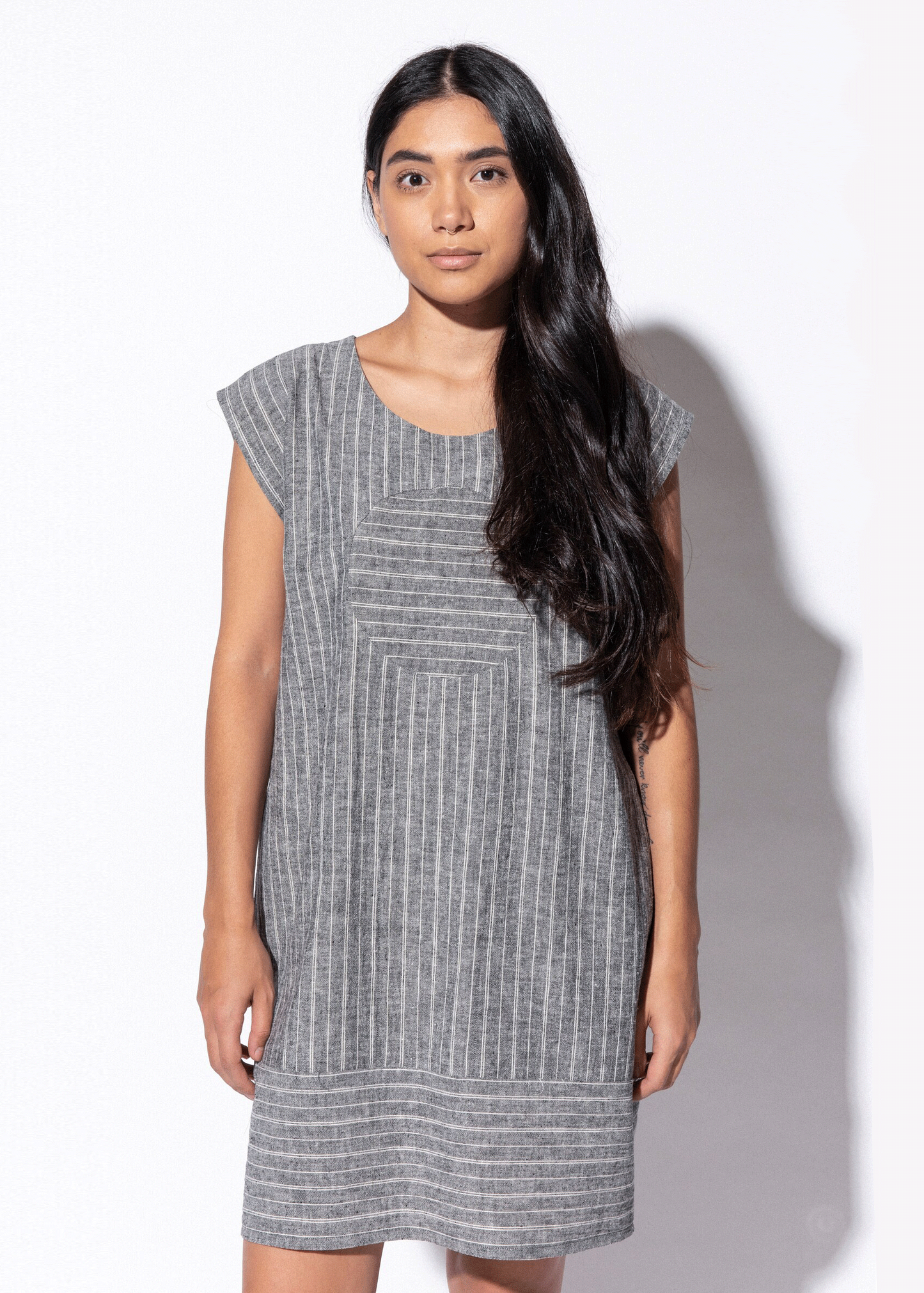 Woman wearing a gray striped dress against a white background