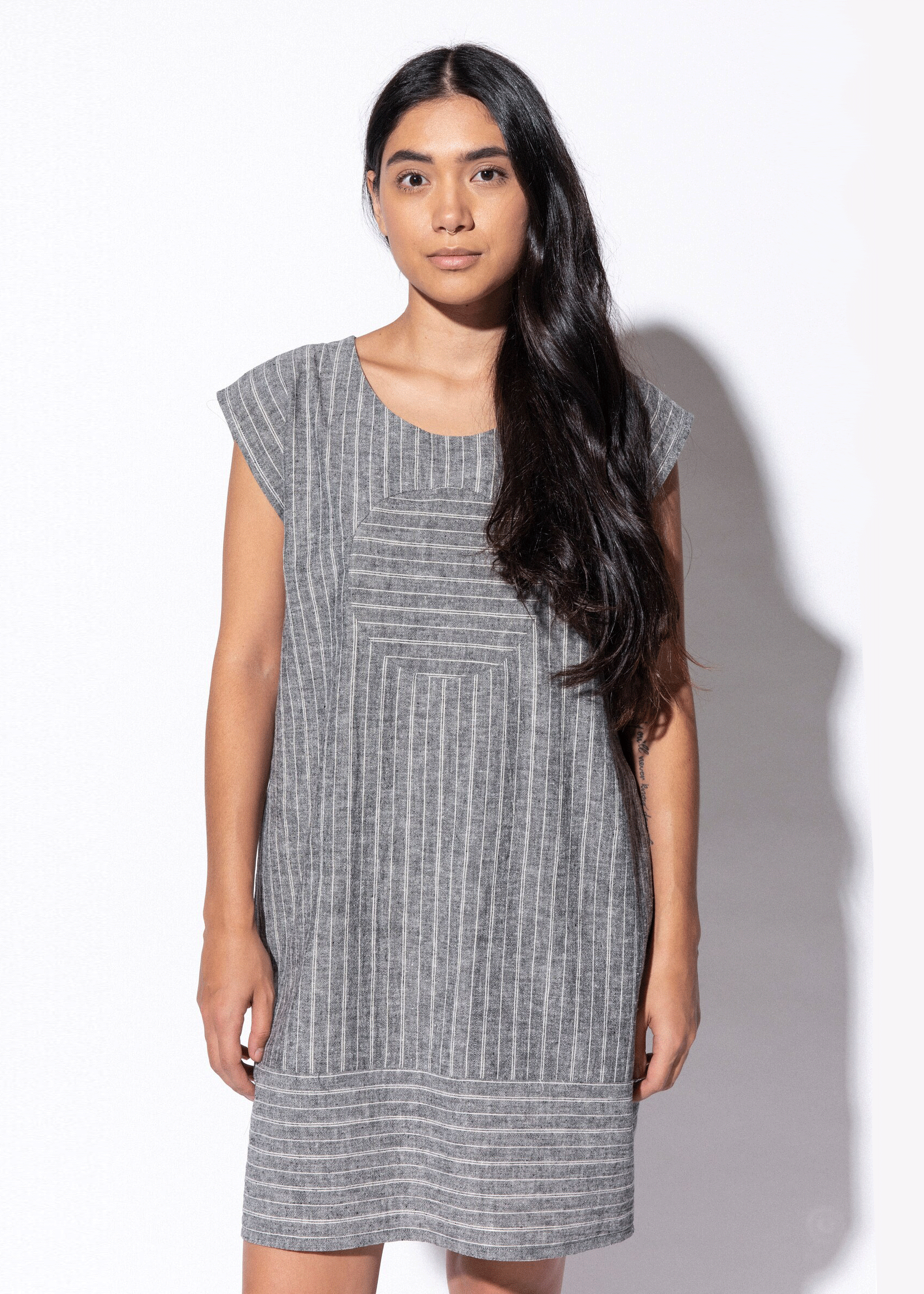 Woman wearing a gray striped dress against a white background