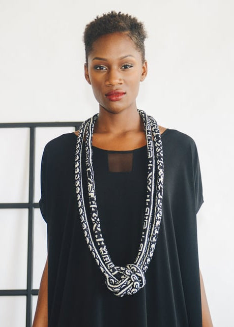 woman wearing black dress and big fabric necklace